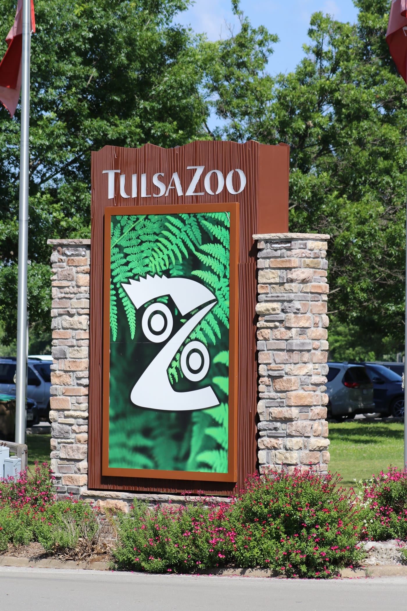 Tulsa Zoo sign between brick pillars and green trees